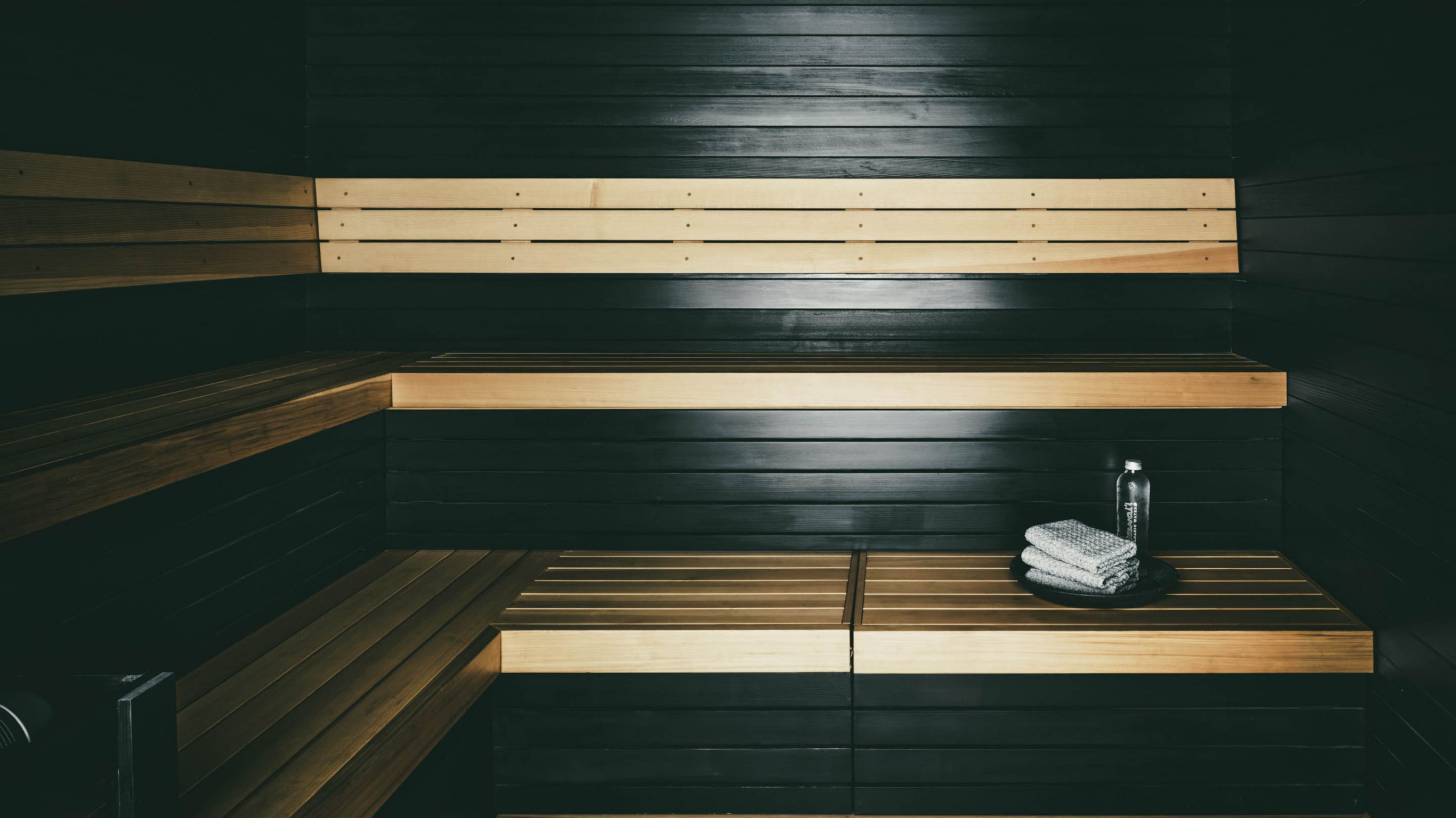 A sauna interior with benches and folded  towels on the lower bench.